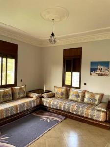 a living room with a couch and windows at Villa avec Piscine, Terrain de Foot et Aire de Jeux pour Enfants in Bir Jedíd Saint-Hubert