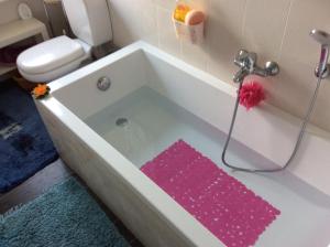 ein Badezimmer mit einer Badewanne und einem rosa Teppich in der Unterkunft Apartment Alina in Cadegliano Viconago