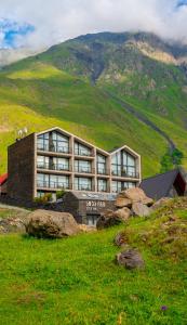 a building on top of a hill with a mountain at Step Inn - Kazbegi in Stepantsminda
