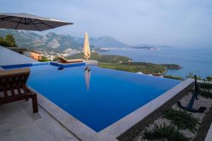 a pool with an umbrella and a view of the water at Villa Infinity in Sutomore