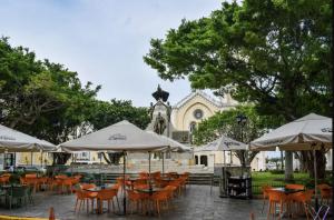 a patio with tables and umbrellas in front of a building at Amazinn Places Teatro Nacional in Panama City