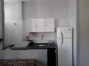 a kitchen with white cabinets and a white refrigerator at Apartamento Gonzaga in Santos