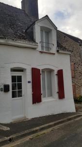 a white house with red shutters and a window at Charming Cottage in a typical French Village in Saint-Christophe-du-Luat