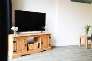 a flat screen tv on a wooden entertainment center at Woodside Ash hot tub & pool (sleeps 4-6) in Bideford