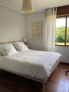 um quarto com uma grande cama branca e uma janela em Perfect Chalet for Beach Lovers and Golfers em Somo