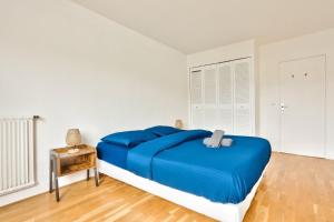 Schlafzimmer mit blauem Bett und Holzboden in der Unterkunft Appartement Quartier Bastille in Paris