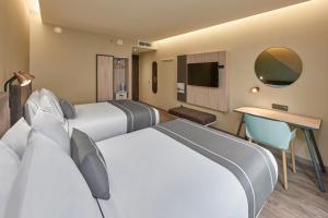 Habitación de hotel con 2 camas y TV en City Express Plus by Marriott Cancun Aeropuerto Riviera en Cancún