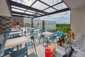 a patio with tables and chairs on a balcony at City Express Plus by Marriott Cancun Aeropuerto Riviera in Cancún