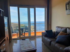 Una sala de estar con un sofá y vista al mar. en Beiramar, en Muxía