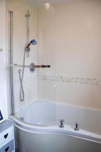 a white bath tub with a shower in a bathroom at Sandy Bottom in Filey