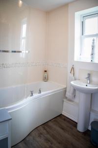 a white bathroom with a tub and a sink at Sandy Bottom in Filey