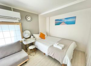 sypialnia z łóżkiem, biurkiem i zegarem w obiekcie KOSUMOSU w Tokio
