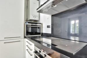 een keuken met witte kasten en een kookplaat oven bij Appartement Quartier Champs-Élysées 4 Free Netflix in Parijs +10 foto's