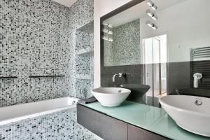 ein Badezimmer mit einem Waschbecken, einer Badewanne und einem Spiegel in der Unterkunft Appartement Quartier Champs-Élysées 4 in Paris