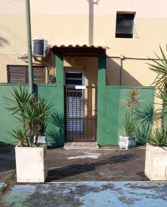 un bâtiment vert avec une porte et quelques plantes dans l'établissement Parque Suites Com Ar Condicionado Piscina e Estacionamento, à Guarujá