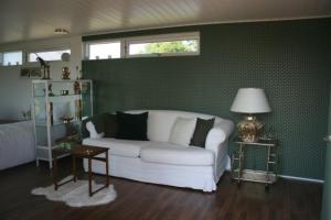 a living room with a white couch and a green wall at Falsterly Glamping in Horbelöv