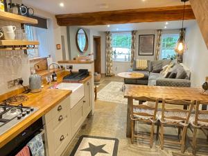 eine Küche und ein Wohnzimmer mit einem Sofa und einem Tisch in der Unterkunft Weavers Cottage, Sleeps 6, outside terrace in Buxton