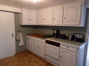 uma cozinha com armários brancos e uma bancada em La Croix de la Roche em Trémuson
