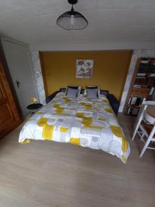 um quarto com uma cama com um edredão amarelo e branco em La Croix de la Roche em Trémuson