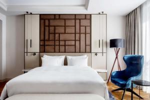 a bedroom with a large bed and a blue chair at Radisson Collection Hotel, Magdalena Plaza Sevilla in Seville