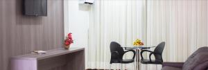 ein Wohnzimmer mit einem Tisch, Stühlen und einem TV in der Unterkunft Monza Palace Hotel in Natal