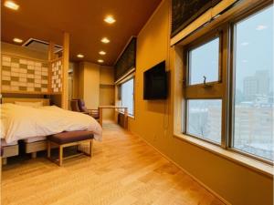 a bedroom with a bed and a tv and windows at Unazuki Onsen Sanyanagitei - Vacation STAY 06553v in Kurobe