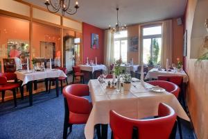 un restaurante con mesas blancas y sillas rojas en Hotel Im Schützenhof, Jever, en Jever