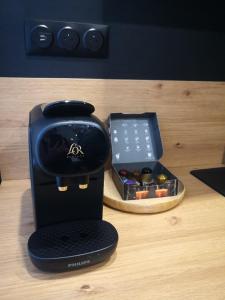 a black coffee maker sitting on a table next to a box at Studio moderne, place parking privé, emplacement idéal à 100 m du lac. in Annecy