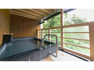 a hot tub in a room with a large window at Unazuki Onsen Sanyanagitei - Vacation STAY 06451v in Kurobe