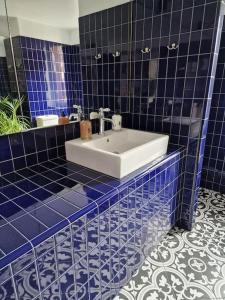 La salle de bains est pourvue de carrelage bleu et d'un lavabo blanc. dans l'établissement Maison Marcks Champagne, à Ay