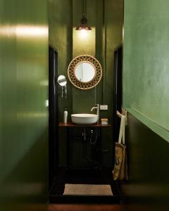 a green bathroom with a sink and a mirror at Motu Bangkok in Bangkok