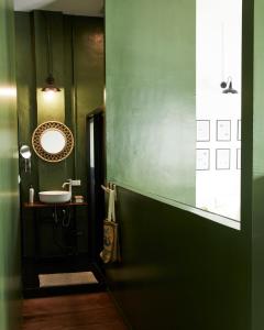 a green bathroom with a sink and a mirror at Motu Bangkok in Bangkok