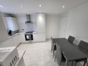Bright Modern 3 Bedroom Apartment في سوتون: مطبخ فيه طاولة سوداء وكراسي