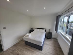 a white bedroom with a bed and a window at Bright Modern 3 Bedroom Apartment in Sutton