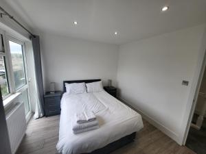 a bedroom with a white bed with two towels on it at Bright Modern 3 Bedroom Apartment in Sutton
