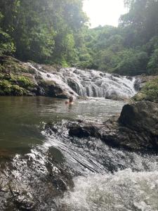 un hombre nadando en un río con una cascada en Mi casita en Montezuma