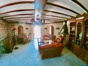una sala de estar con muebles de cuero y una lámpara de araña. en Magnífico Castillo privado, elevado en la roca, en La Cabrera