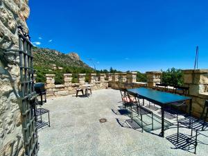 um pátio com uma mesa azul e cadeiras numa parede de pedra em Magnífico Castillo privado, elevado en la roca em La Cabrera