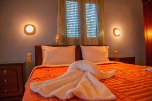 1 dormitorio con 1 cama naranja con sábanas blancas y 2 ventanas en Studios Ristas 2, en Parga