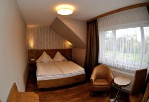 a bedroom with a bed and a window and a chair at Gasthof Vossbur in Toppenstedt