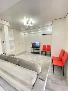a living room with a couch and two red chairs at RentNow Family Large Apartament near Airport in Chişinău