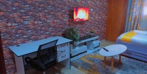 a bedroom with a stone wall with a desk and a television at Kathy's Place in Runda in Nairobi