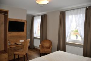 a bedroom with a bed and a desk and a television at Gasthof Vossbur in Toppenstedt