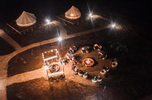 una vista in alto di un gruppo di persone sedute intorno a un tavolo di notte di Terranova Glamping a Luján