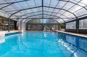 an indoor swimming pool with a glass roof at Terranova Glamping in Luján