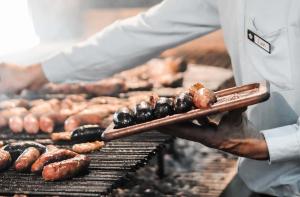 a chef is cooking sausages on a grill at Terranova Glamping in Luján