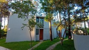 une maison blanche avec des arbres devant elle dans l'établissement Lucero, à Mar Azul