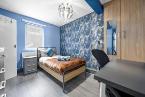 Schlafzimmer mit blauen Wänden, einem Bett und einem Schreibtisch in der Unterkunft Private retreat for 3 Near Arndale City Centre in Manchester