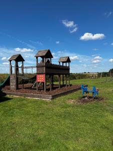 a playground with a slide and two benches in a field at Happy Place in West Mersea