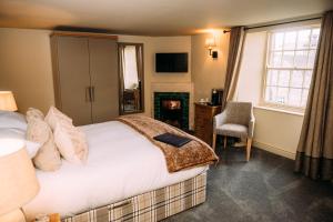 a bedroom with a bed and a chair and a fireplace at The Assheton Arms in Clitheroe